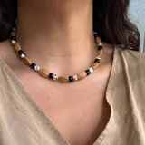Collar corto de cuentas de madera color camel, con cuentas redondas negras y blancas con diseño moteado.