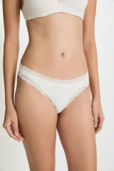 Bombacha tipo vedetina de color blanco, con detalle de encaje en la cintura y los bordes. Confeccionada en poliamida y elastano con forro de algodón.