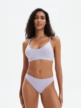 Conjunto de ropa interior color lila, compuesto por un corpiño tipo bralette de breteles finos y una bombacha tipo tanga. Ambos con detalles de encaje en los bordes.