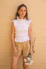 Blusa blanca de algodón con textura fruncida y detalles de broderie en cuello, mangas y ruedo.