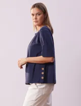 Blusa azul de algodón marca Erika, de manga corta amplia y cuello redondo. Presenta aberturas laterales con botones.