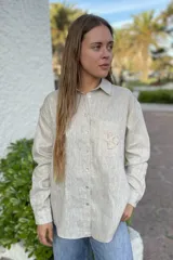 Camisa color beige con cuello, cierre frontal con botones y manga larga.
