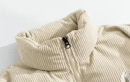 Campera puffer marrón con parte superior de pana y bordado blanco en la espalda con la palabra "Chingona". Tiene tiras regulables en la cintura.