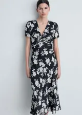 Vestido midi negro con estampado floral blanco, escote en V, mangas cortas y detalle fruncido en la cintura.
