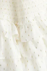 Minifalda blanca con lunares dorados, cintura elastizada y tres niveles de volados.