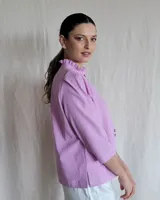 Camisa blanca de mangas 3/4 con cuello mao y botones frontales.