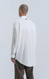 Camisa blanca de manga larga con bolsillo en el pecho, de calce oversize confeccionada en textil fresco y liviano.