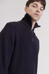 Sweater de punto color crema con cuello alto y cierre de cremallera parcial. Diseño de corte holgado y mangas largas.