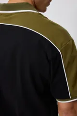 Remera polo negra con corte en hombros y mangas en color verde oliva, con ribete blanco.