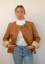 Chaqueta reversible de cuero color marrón claro, con cuello redondo y cierre con botones a presión.