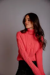 Sweater verde esmeralda de punto trenzado, con cuello alto y mangas largas.