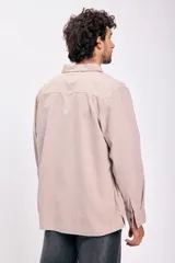 Camisa de manga larga color beige con botones negros.