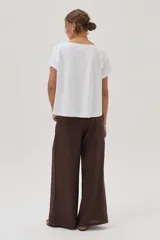 Remera blanca de algodón con estampa de palmeras y la palabra "Sunrise" en el frente.