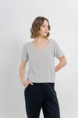 Remera tejida de manga corta, color gris claro, con escote en V y calce relajado. Presenta terminaciones acanaladas en mangas y ruedo.