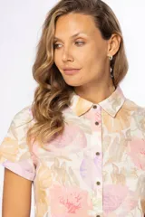 Camisa de manga corta con estampado floral en tonos pastel, cuello clásico y cierre frontal con botones.