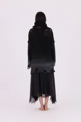 Sweater de punto grueso con cuello tortuga, diseño oversize y efecto degradé de negro a gris oscuro en la parte inferior. Presenta roturas intencionales en el ruedo y puños, con un tejido calado visible en la zona del cuello.