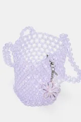 Bolso mini tipo saca cilíndrica con cuerpo de cuentas brillantes color lila. Interior de tela satinada con cierre fruncido y doble asa de mano. Incluye charm extraíble.