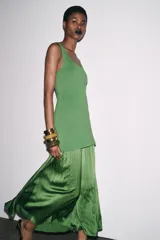 Vestido largo verde con escote redondo y sisas amplias. La parte superior es de punto liso y la falda es plisada de tejido satinado.