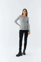 Remera gris de punto canalé, con escote redondo y mangas largas.