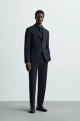 Pantalón de vestir gris oscuro, corte slim fit, confeccionado en tejido con 17% de lana. Cuenta con bolsillos frontales y traseros de vivo con botón. Cierre frontal con cremallera y botón.