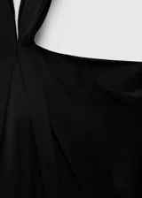 Mono largo negro de tejido fluido con cuello halter, detalle de nudo en el cuello y cierre de cremallera en la espalda.
