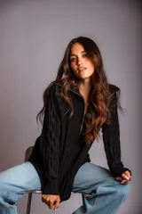 Buzo de punto color rosado, con cuello polo y cierre frontal parcial, de manga larga y diseño holgado.