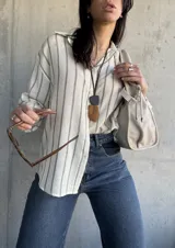 Camisa a rayas verticales color crudo y gris, de corte holgado y mangas largas con puños abotonados.