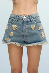 Short de jean celeste con bordados de canutillos y lentejuelas beige con formas asimétricas. Tiene roturas y terminación desflecada.