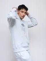 Canguro negro de felpa sin frisa con capucha y logo Umbro bordado en rojo en el pecho. Cuenta con bolsillo tipo canguro y cordones ajustables en la capucha.