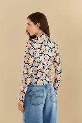 Top de cuello alto y mangas largas con estampado floral multicolor sobre fondo negro.