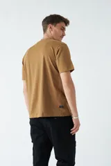 Remera color ocre de corte recto y manga corta, con cuello redondo y estampado rectangular con diseño floral en el frente.