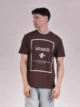 Remera marrón de manga corta con estampa frontal que incluye la palabra 'Venice', un oso con una tabla de surf y la frase 'Venice Beach, California - Locals Only'.