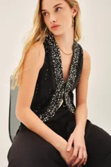 Chaleco negro con lentejuelas y apliques plateados, escote en V y cierre frontal con gancho oculto.