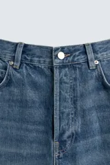 Pantalón de jean azul de tiro medio, corte flare, con cinco bolsillos y cierre frontal con cremallera y botón.