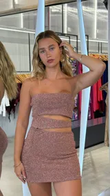 Minivestido strapless color rosa con brillos, corte ajustado y abertura en la cintura.