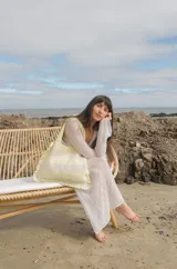 Bolso tipo tote tejido a crochet, con hilo 100% algodón, a rayas horizontales color crema y lila, con volados en los bordes y manijas reforzadas.