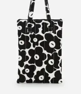 Funda para notebook con diseño tipo cartera, confeccionada en algodón con estampado floral bicolor en blanco y negro. Tiene cierre de cremallera y asa mediana.
