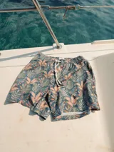 Short de baño blanco con estampado de hojas de palmera en tonos verde, rojo y amarillo.