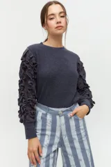 Remera negra de punto con mangas largas abullonadas con volantes.