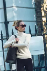 Jersey de punto color blanco, de cuello alto y manga larga con detalle de botones en el puño.