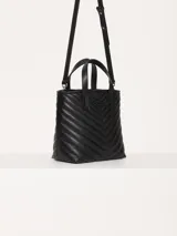 Cartera tote pequeña de cuero sintético negro con diseño acolchado en forma de espiga. Tiene doble asa corta superior, correa larga ajustable y desmontable, y logo metálico frontal con forma de labios.