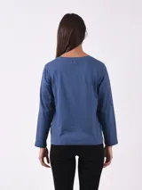 Remera de manga larga color azul oscuro con estampado de pequeñas hojas o puntos en blanco/gris claro. Presenta detalles de botones dorados en el escote del hombro.