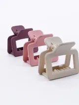 Set de tres pinzas para el pelo tipo clip, de plástico transparente en color negro, marrón y beige.