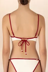 Top de bikini triangular color marfil con ribete rojo oscuro, tirantes finos con anillos dorados y faja inferior.