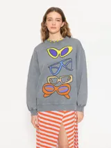 Buzo gris con cuello redondo, mangas largas y estampado de anteojos de diferentes colores en el frente.