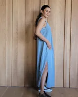 Vestido largo color crudo, sin mangas y con escote en V. Presenta aberturas laterales en el ruedo y bolsillos laterales a la altura de la cadera.