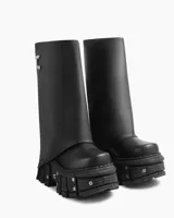 Bota negra de cuero ecológico con caña alta asimétrica y suela track con detalles metálicos.