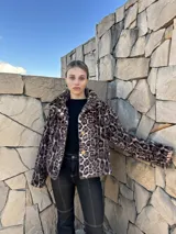 Chaqueta corta de gamulán sintético con estampado animal print, cuello solapa y cierre frontal con botones dorados.