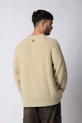 Sweater marrón de punto con cuello redondo y mangas largas raglán. Tejido grueso con textura acanalada. Corte holgado.