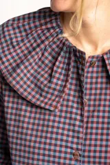 Camisa a cuadros azul y rosa con cuello babero, mangas largas abullonadas y cierre frontal con botones.